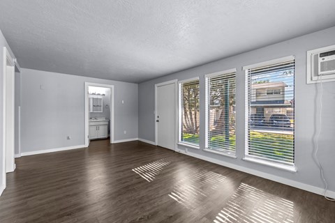 an empty living room with windows and wood floors